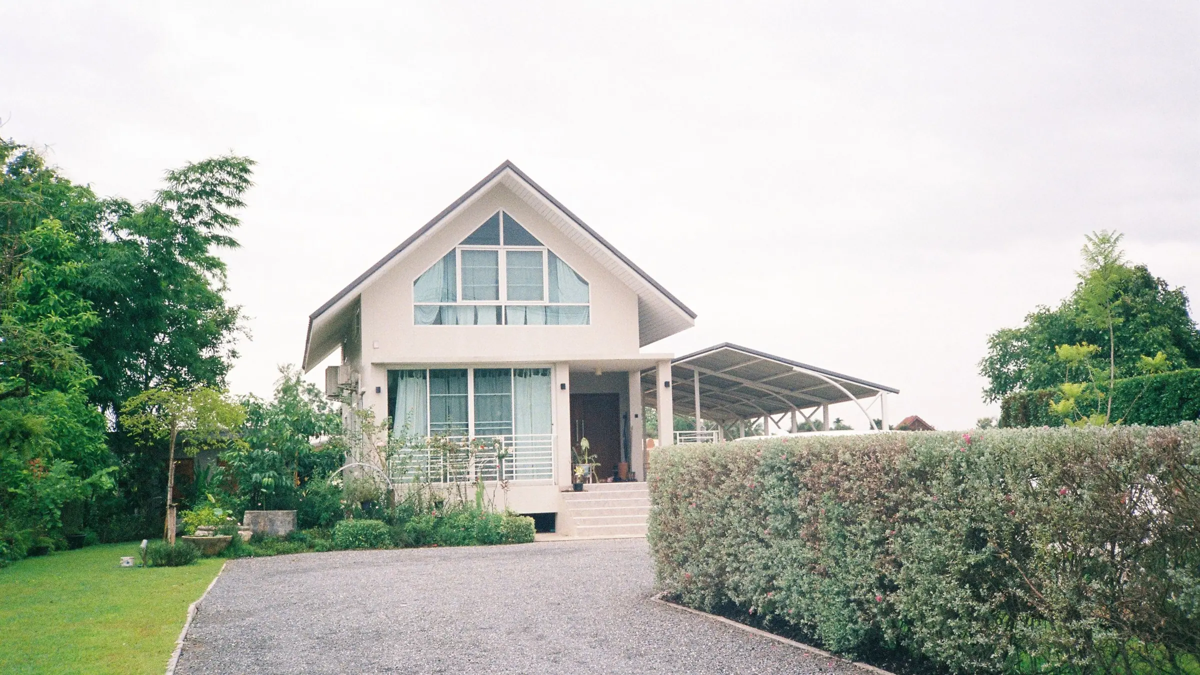 A family home with a gable roof at the end of a gravel driveway