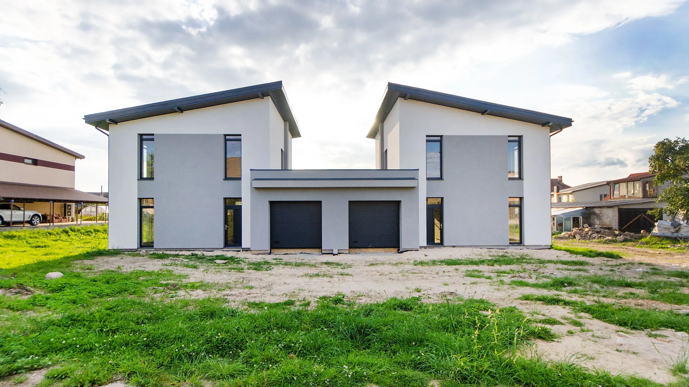 Two family homes with gable roofs side by side on a grassy plot