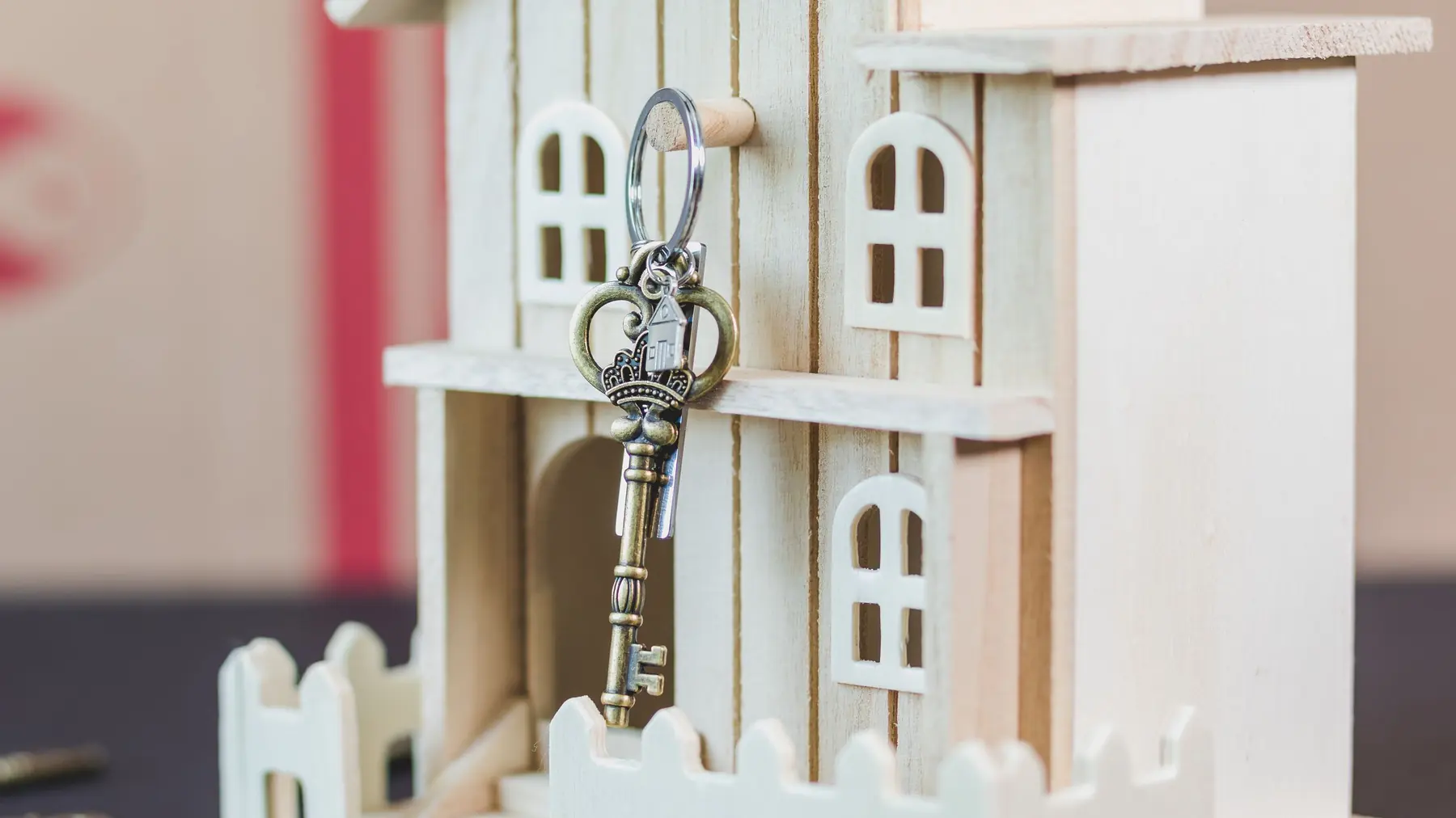 A small white model house with a key hanging from it