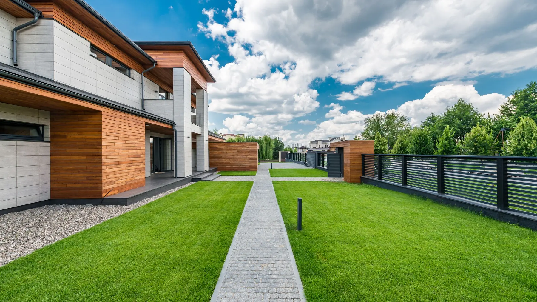 A paved path between modern homes and a green lawn
